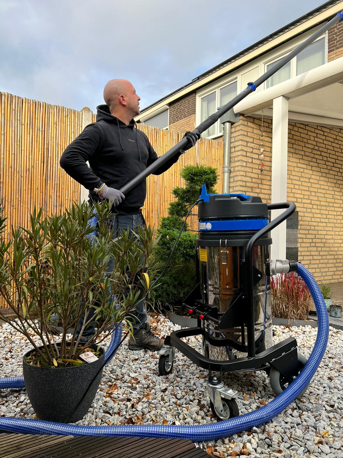GOOT-BUSTERS medewerker met zuigunit en telescoopstok bij een woning