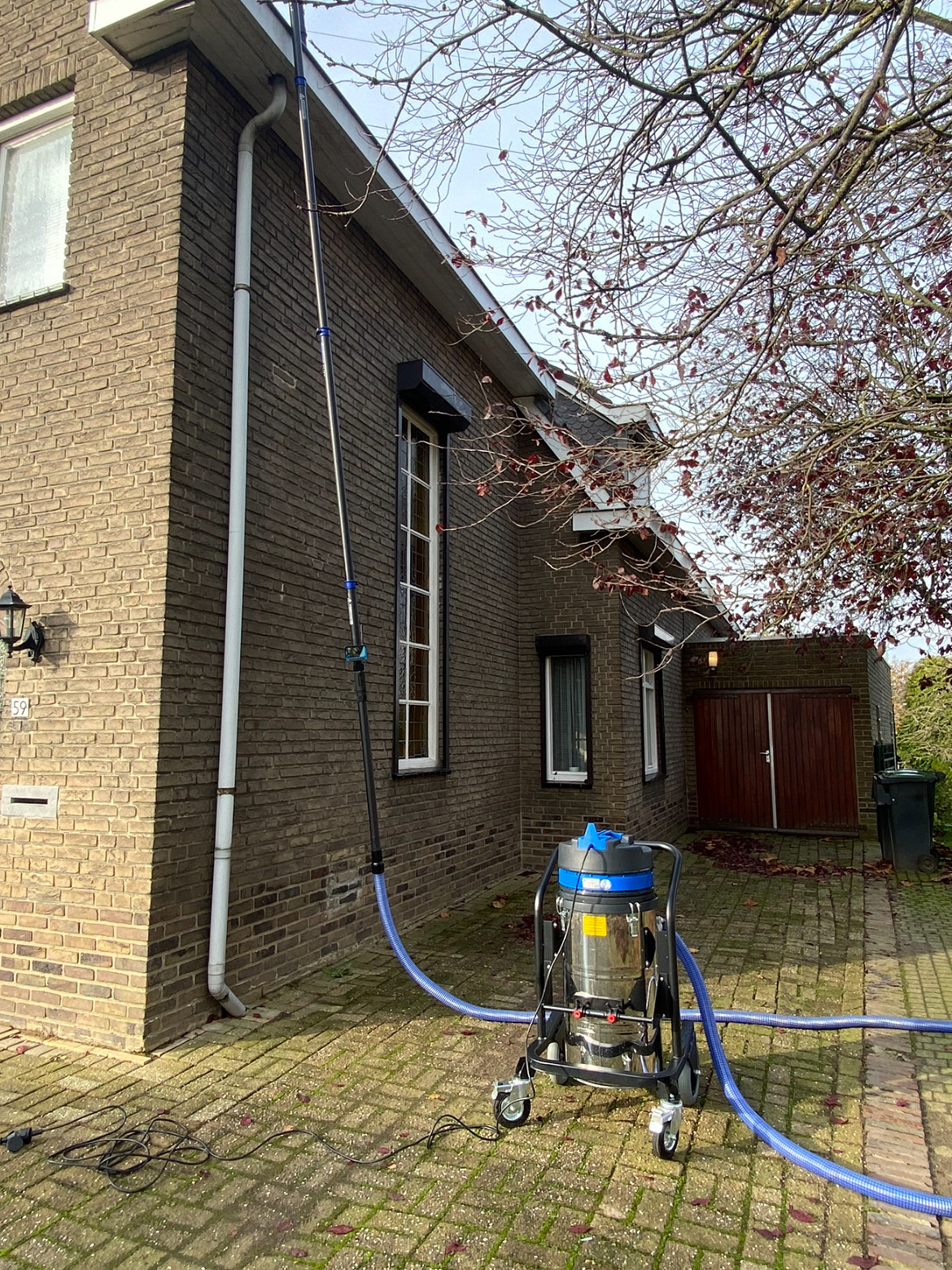 Professionele zuigunit met slang bij een woning