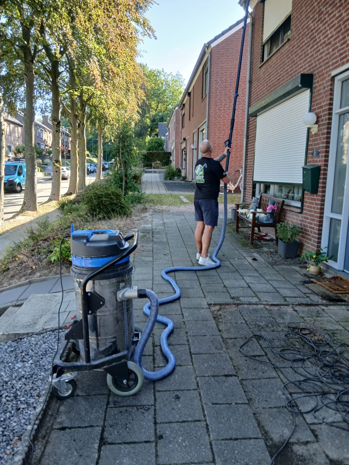 GOOT-BUSTERS medewerker houdt de telescoopstok met inspectiescherm omhoog bij een rijtjeshuis